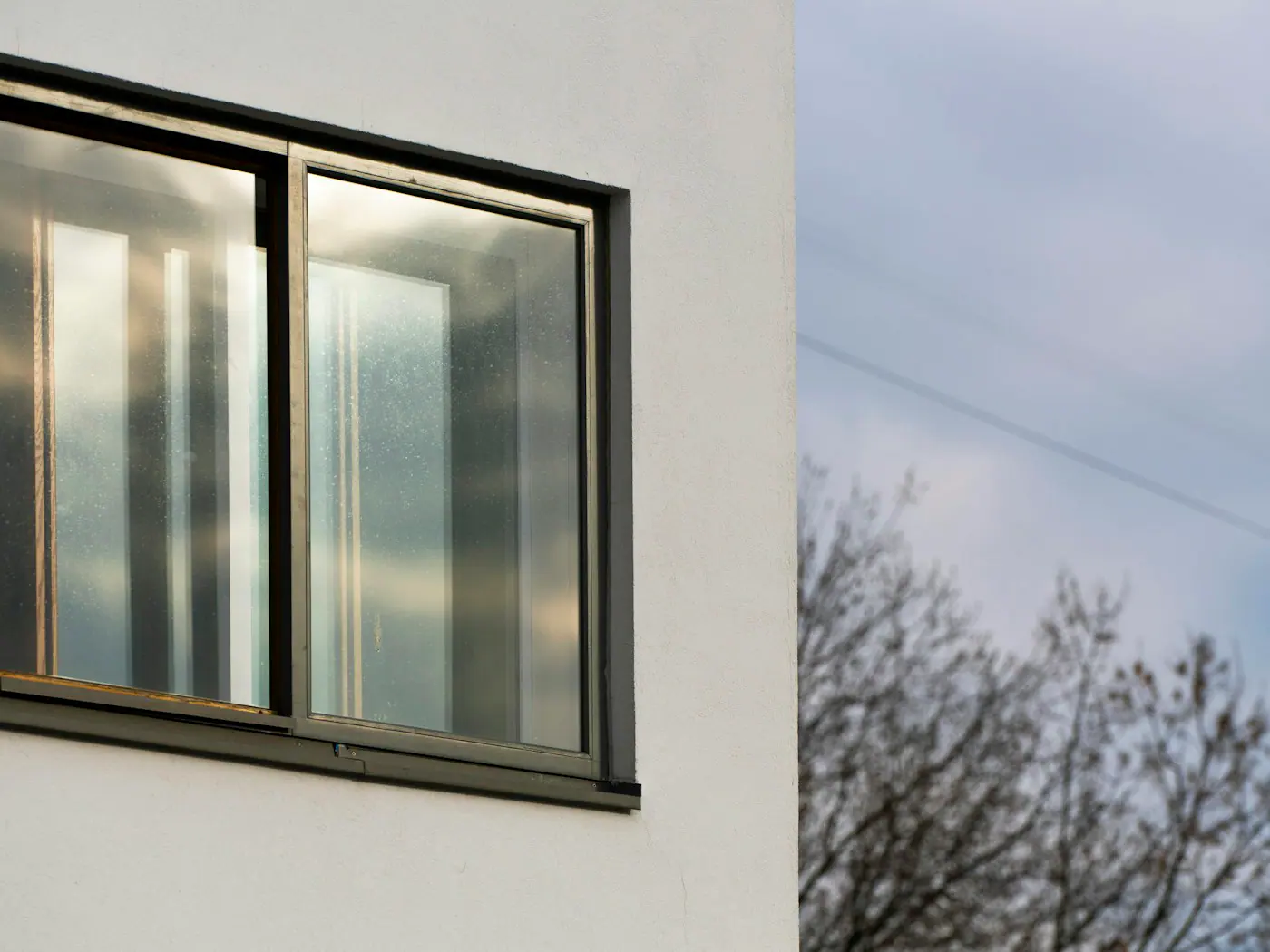 Dark grey aluminium sliding window set in a white rendered wall