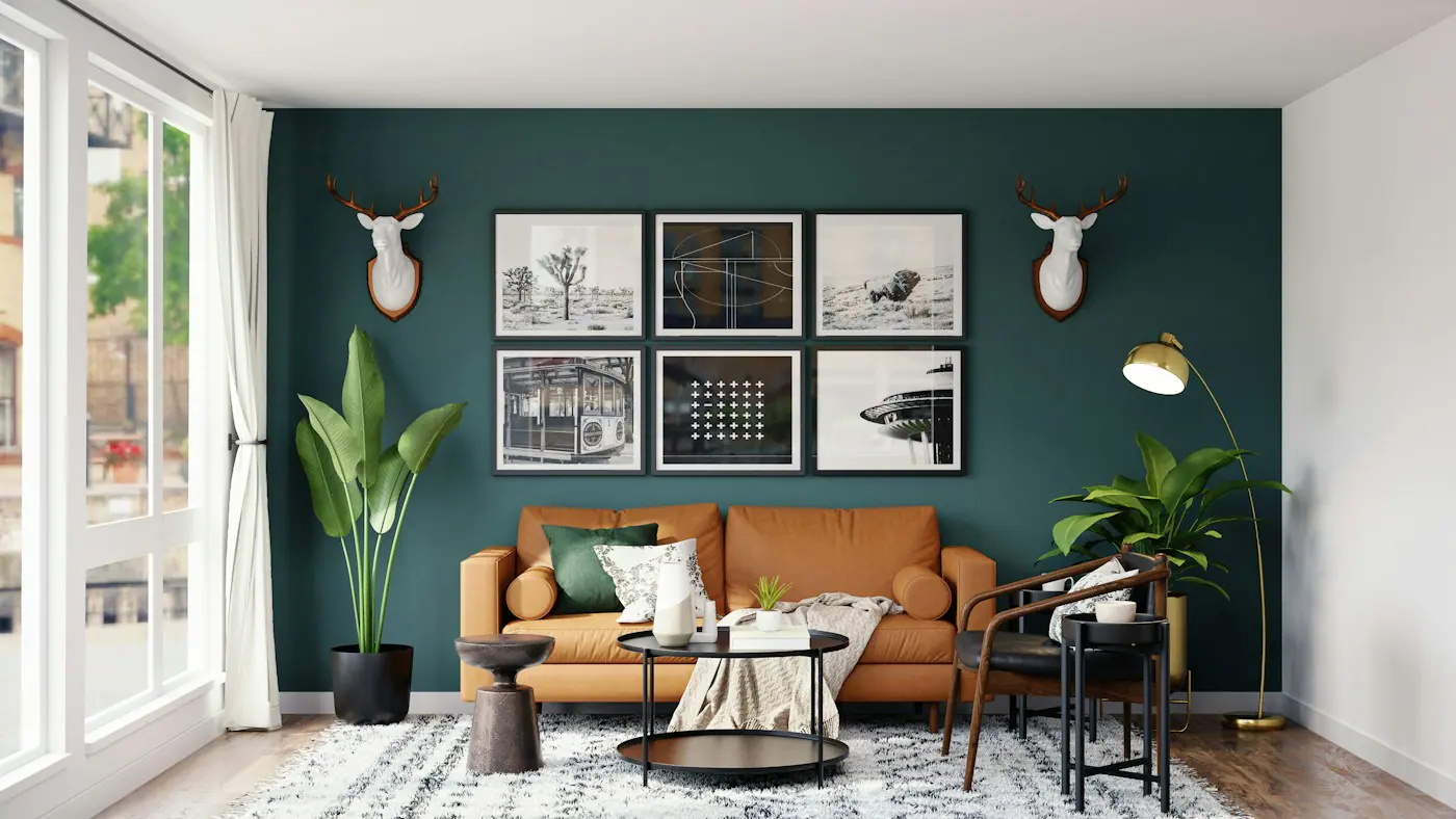 Living room with a deep teal accent wall, tan leather sofa, framed black-and-white prints and floor lamp